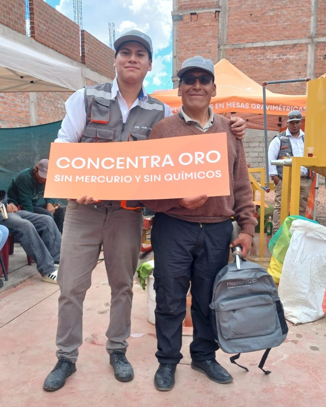 Cliente de Meproind con el cartel «Concentra oro sin mercurio y sin químicos» junto a un técnico en la planta
