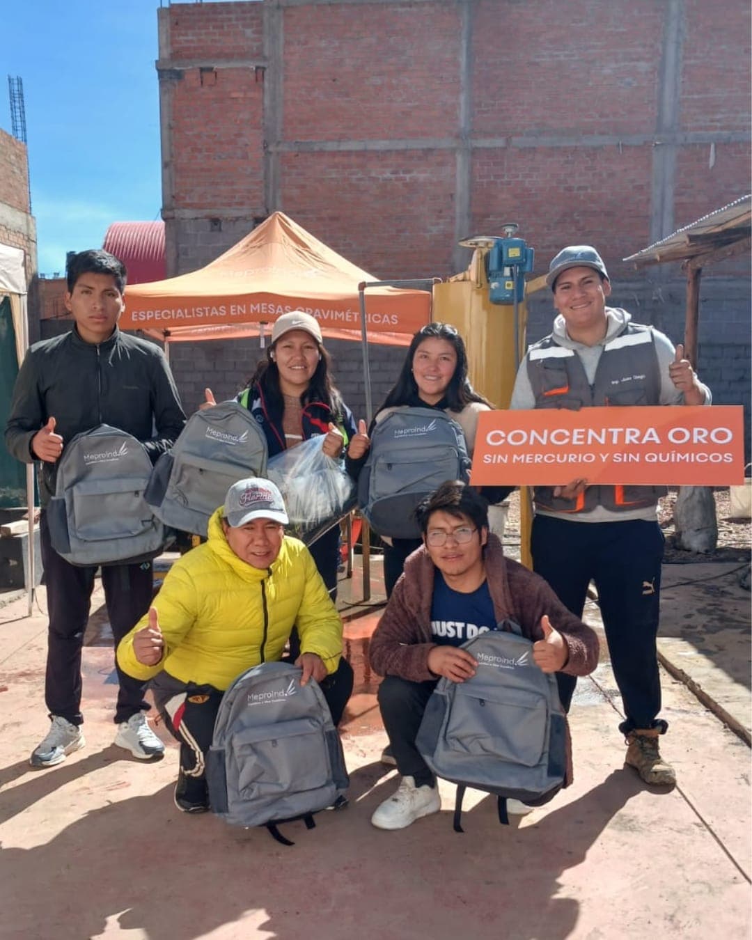 Grupo de mineros capacitados por Meproind con sus mochilas y el cartel de concentración sin mercurio