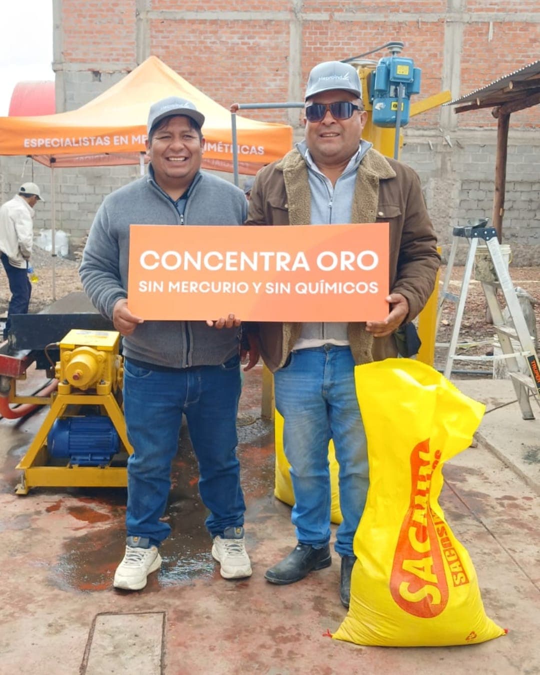 Dos clientes de Meproind junto a la mesa gravimétrica en operación, con el cartel de concentración sin químicos